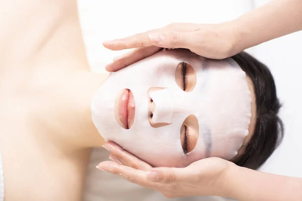 Young beauty with facial mask in spa salon — Stock Photo, Image