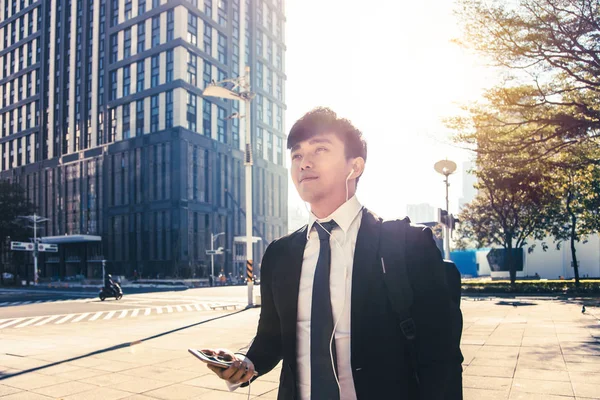 Uomo d'affari che tiene il telefono cellulare mentre cammina sulla strada per offi — Foto Stock