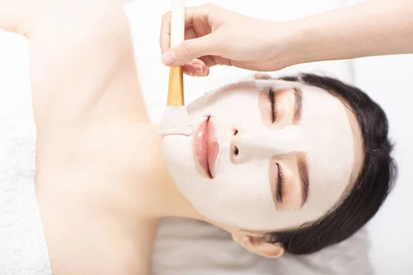 Giovane donna con maschera sul viso nel salone di bellezza spa — Foto Stock