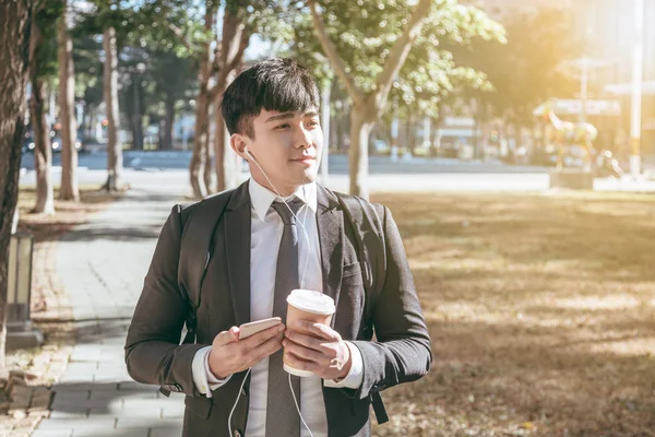 Affärsman som håller mobiltelefon när han går på gatan till offi — Stockfoto