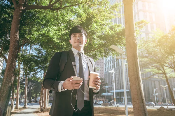 Podnikatel držící mobilní telefon při chůzi na ulici do kanceláře — Stock fotografie