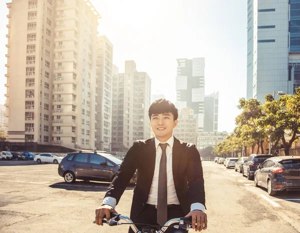 Businessman riding bicycle to work on urban street at morning
