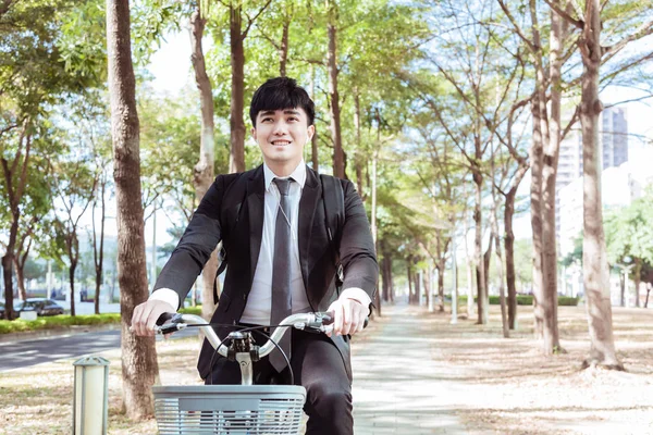 Businessman riding bicycle to work on urban street at morning — Stock Photo, Image