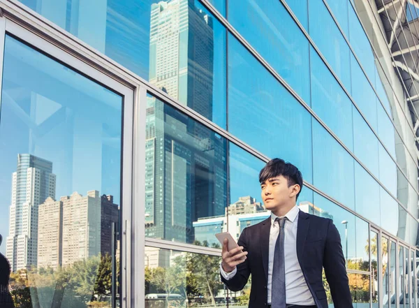 Hombre de negocios utilizando el teléfono móvil y de pie frente a offic — Foto de Stock