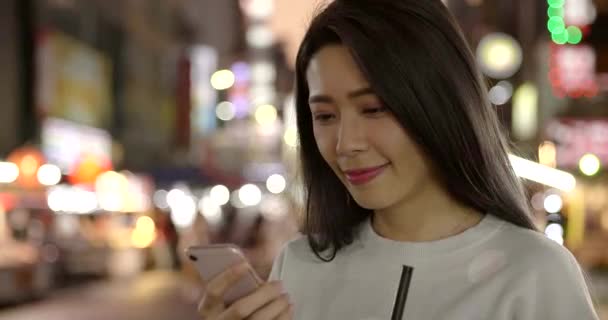 夜市内でスマートフォンを見ている若い女性 — ストック動画