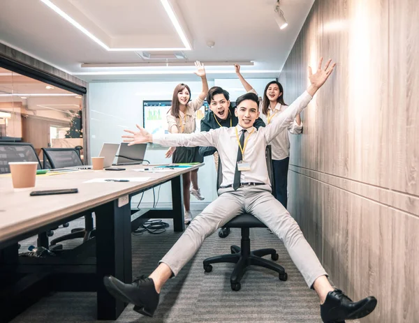 Бізнесмени весело катаються на стільцях в офісі — стокове фото
