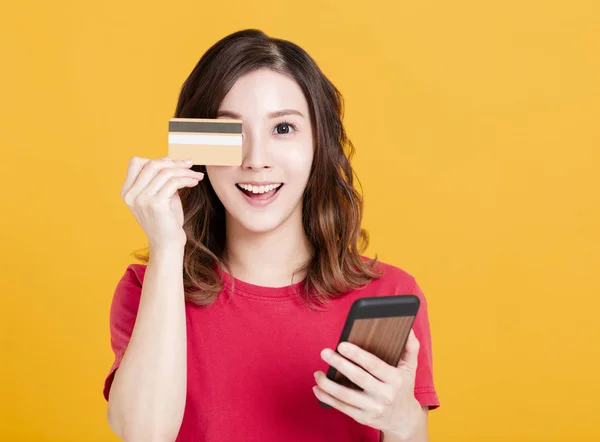 Šťastná mladá žena držící chytrý telefon a kreditní karty. — Stock fotografie