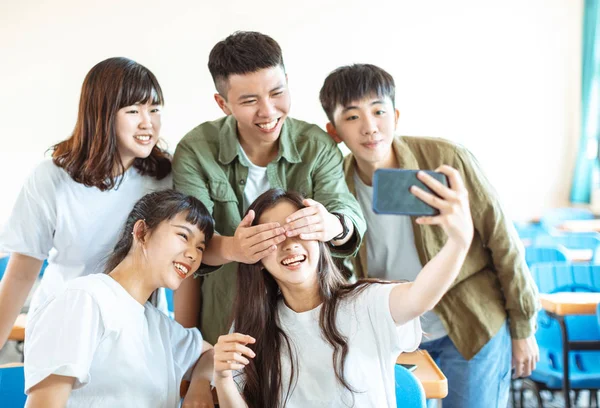 Fröhliche junge Gruppe von Teenagern macht lustiges Selfie im Klassenzimmer — Stockfoto