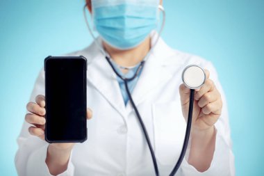 Steteskoplu bir doktor ve tıbbi muayene için elinde akıllı telefon var.