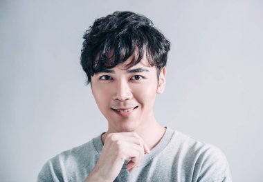  Gri arka planda izole edilmiş gülümseyen yakışıklı bir adamın portresi.