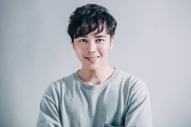  Gri arka planda izole edilmiş gülümseyen yakışıklı bir adamın portresi.