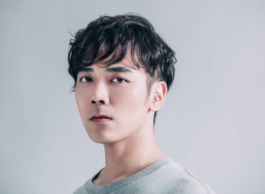  Gri arka planda izole edilmiş genç yakışıklı adamın portresi.