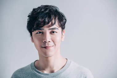  Gri arka planda izole edilmiş gülümseyen yakışıklı bir adamın portresi.