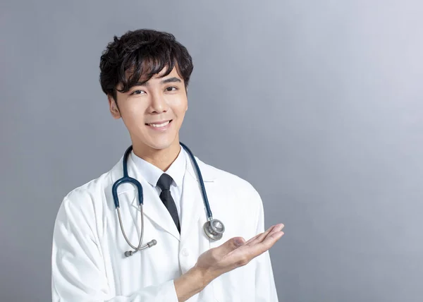 Młody Azjatycki Lekarz Patrząc Aparat Wskazując Daleko — Zdjęcie stockowe