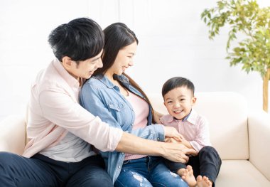 Mutlu aile oynuyor ve oturma odasındaki kanepede oturuyor.