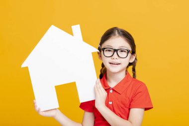 Mutlu küçük kız ev modelini gösteriyor ve tutuyor.