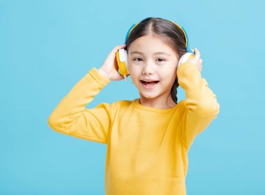 Mutlu küçük kız kulaklıkla müzik dinliyor.