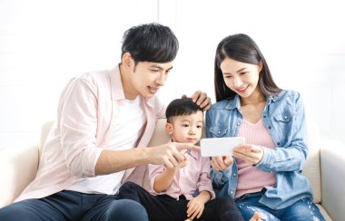 Mutlu aile koltukta akıllı telefonu izliyor.