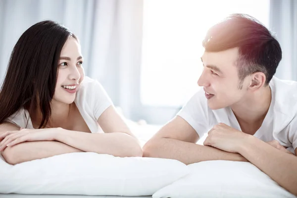 快乐的年轻夫妇面面相觑 躺在床上笑着 — 图库照片