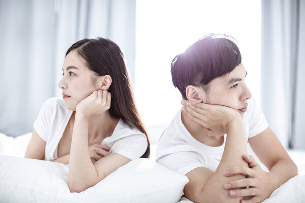 young Couple sitting back to back on bed during  conflict