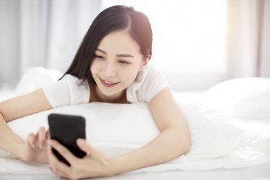 Kadın yatakta uyanıyor ve ben akıllı telefona bakıyorum.