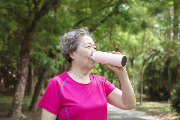 亚洲老年妇女运动后喝水 — 图库照片