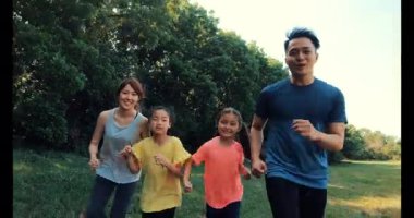 Mutlu Aile, parkta koşan ya da koşan iki kız.