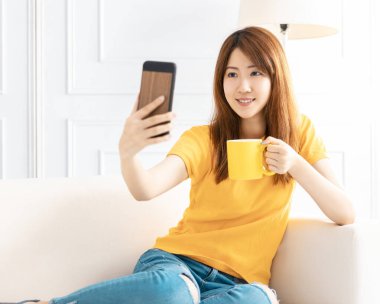 Gülümseyen genç bir kadın. Telefondaki görüntülü konuşma.