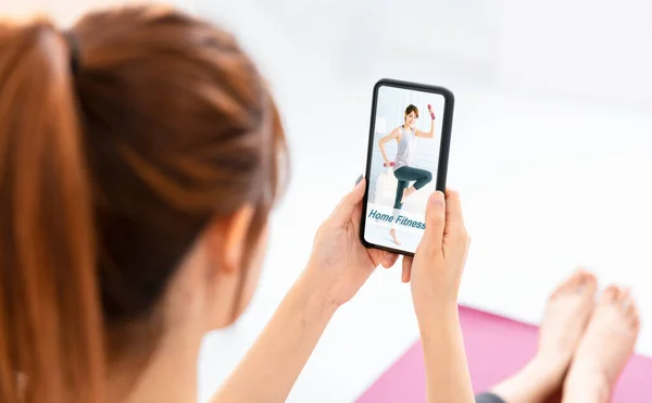 Young  woman watching mobile phone training lesson app  doing exercises at home