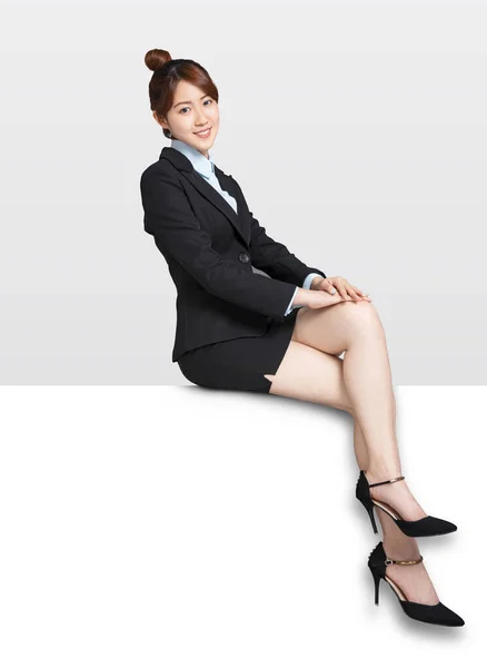 青い看板の看板に座っている若いビジネスマン女性 — ストック写真