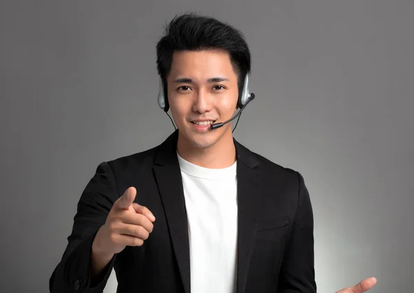 Usmívající Mladý Asijský Podnikatel Mluví Sluchátka Proti Šedé Pozadí — Stock fotografie