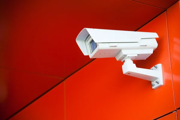 Security camera on the red wall — Stockfoto