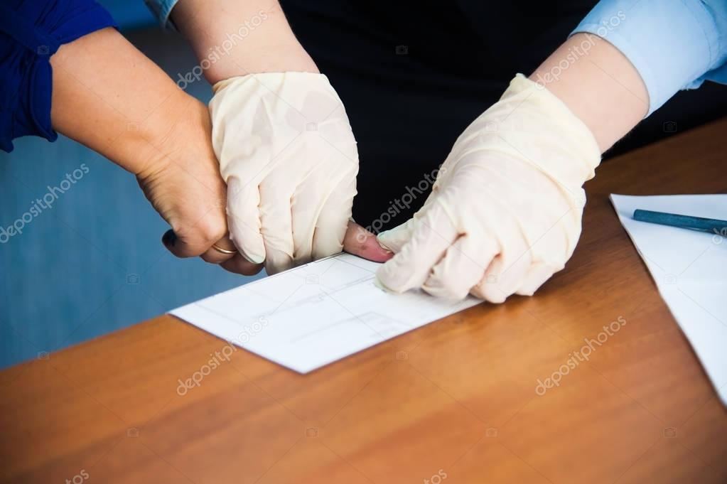 The inspector takes fingerprints of a suspect
