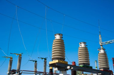 Mavi gökyüzü arka planında yüksek voltajlı güç transformatörü.