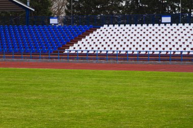Gökyüzü bulutlu ve yeşil çimenleri olan açık hava stadyumu