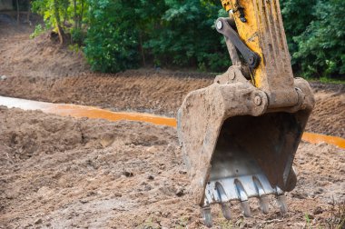 İnşaat alanında toprağı temizlemeye çalışan bir kazıcı.