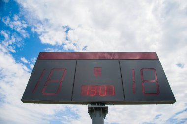 Mavi gökyüzüyle futbol stadyumunda skor tablosu