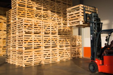 Sebze depolamak için büyük bir depoda forklift. Depoda katlanmış boş ahşap kutular, meyve ve sebze toplamak için kutular tasarlanmıştır.