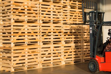 Sebze depolamak için büyük bir depoda forklift. Depoda katlanmış boş ahşap kutular, meyve ve sebze toplamak için kutular tasarlanmıştır.