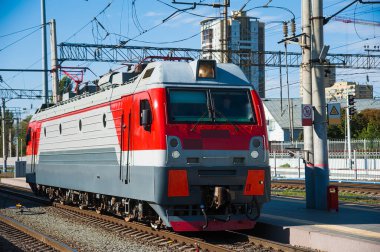 Tren raylarında ve demiryolu platformunda kırmızı tren lokomotifi. Tren ve tren istasyonu.