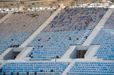 Stadyum inşaatı. Bir futbol stadyumunun inşaatı için inşaat malzemeleri ve işçiler. Koltuklar tribünde. Stadyumda çimensiz