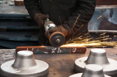 Metal üreten adam kıvılcımlar üretiyor. İş yerinde bir adam. Metal işleme, metal kesme ve bitirme. Metal endüstrisi