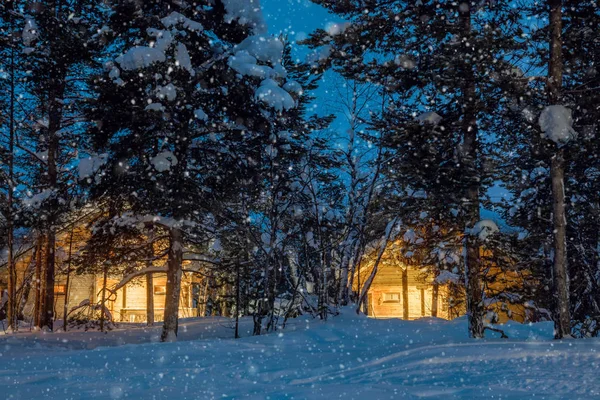 Снежная ночь, маленькие деревянные домики с теплым светом — стоковое фото