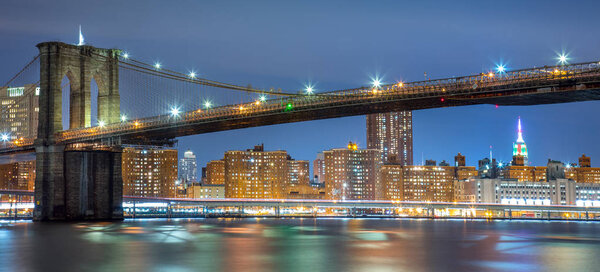 Panoramic view of Brooklyn Bridge at night with lights, New York City, USA