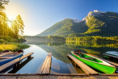 Sabahın erken saatlerinde göl kenarında tekneler ve dağlarla. Güzel güneşli bir tatil - dinlenme, manzara