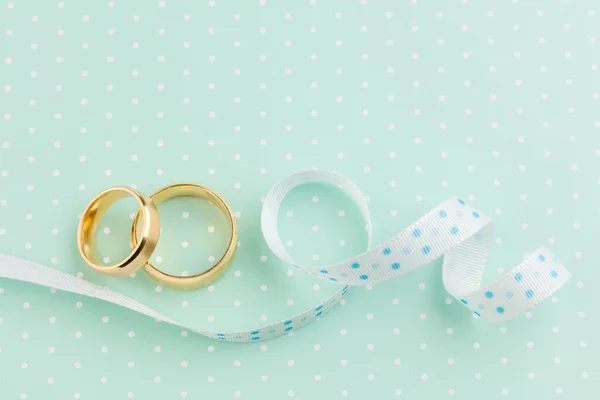 婚礼背景 浅绿色背景的两个结婚戒指和彩带 — 图库照片