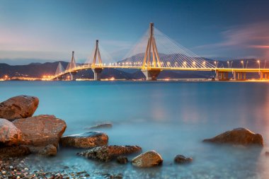 Gece vakti ışıklarla modern köprü. Rion-Antirion Köprüsü, Yunanistan, Avrupa. Yunanistan 'daki Rion-Antirion Köprüsü dünyanın en uzun kablo destekli köprülerinden biri ve tamamen askıya alınmış türlerin en uzunu.