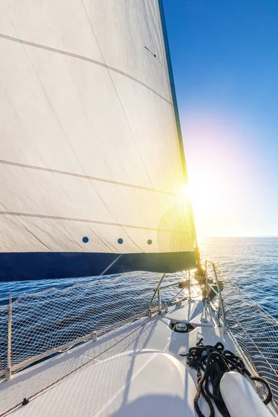 Sailing with sun. A view from the yacht\'s deck to the bow and sails. Sail boat with set up sails gliding in open sea. Greece, Europe