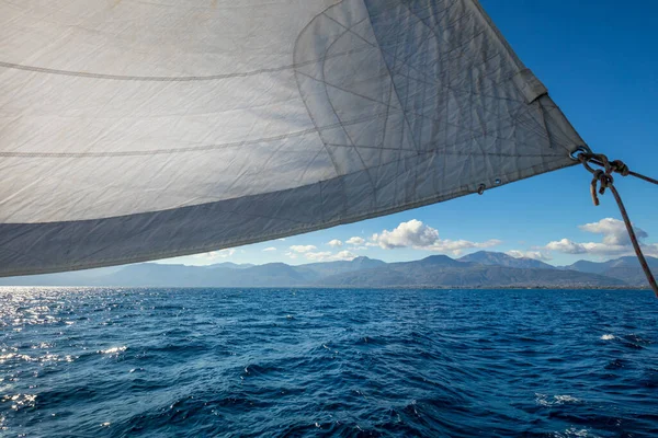 Sail boat with set up sails gliding in open sea near islands, Greece