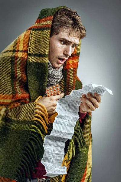 Man covered in blanket reads to instructions.